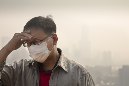 Man using a disposable mask having headache because of haze