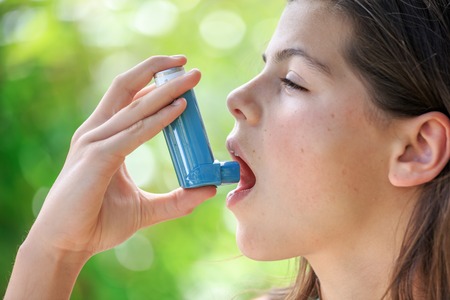 Girl with Asthma using a asthma inhaler