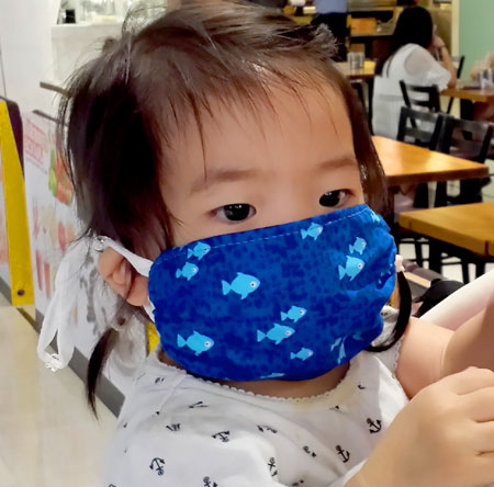 Toddler wearing a Breathe Healthy Reusable Anti Microbial Face mask fish design